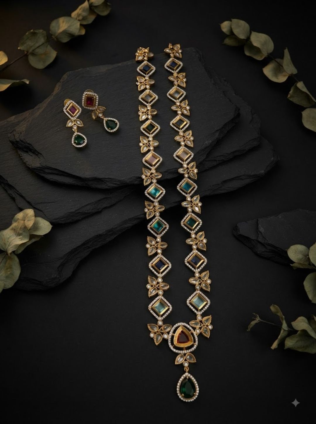 Long South Indian necklace with emerald, ruby and blue-toned stones and matching drop earrings.

Designer gemstone necklace set featuring floral details, geometric stones and a statement pendant.