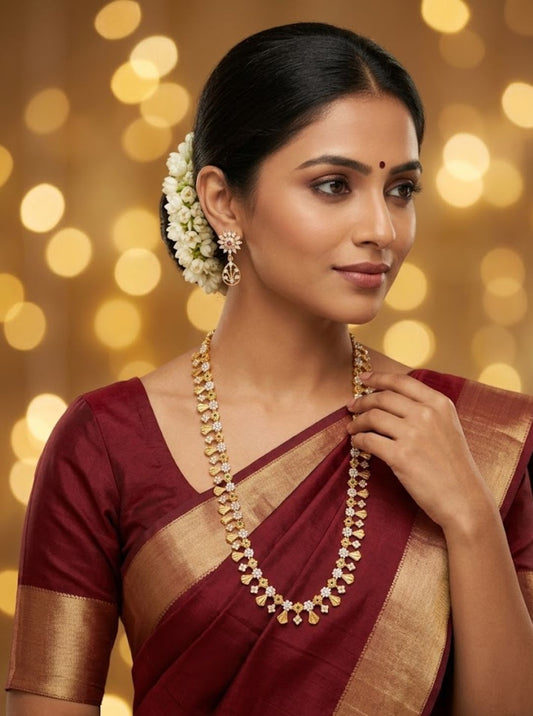 Elegant gold floral necklace set with sparkling stones and green accents displayed on a wooden jewellery board.