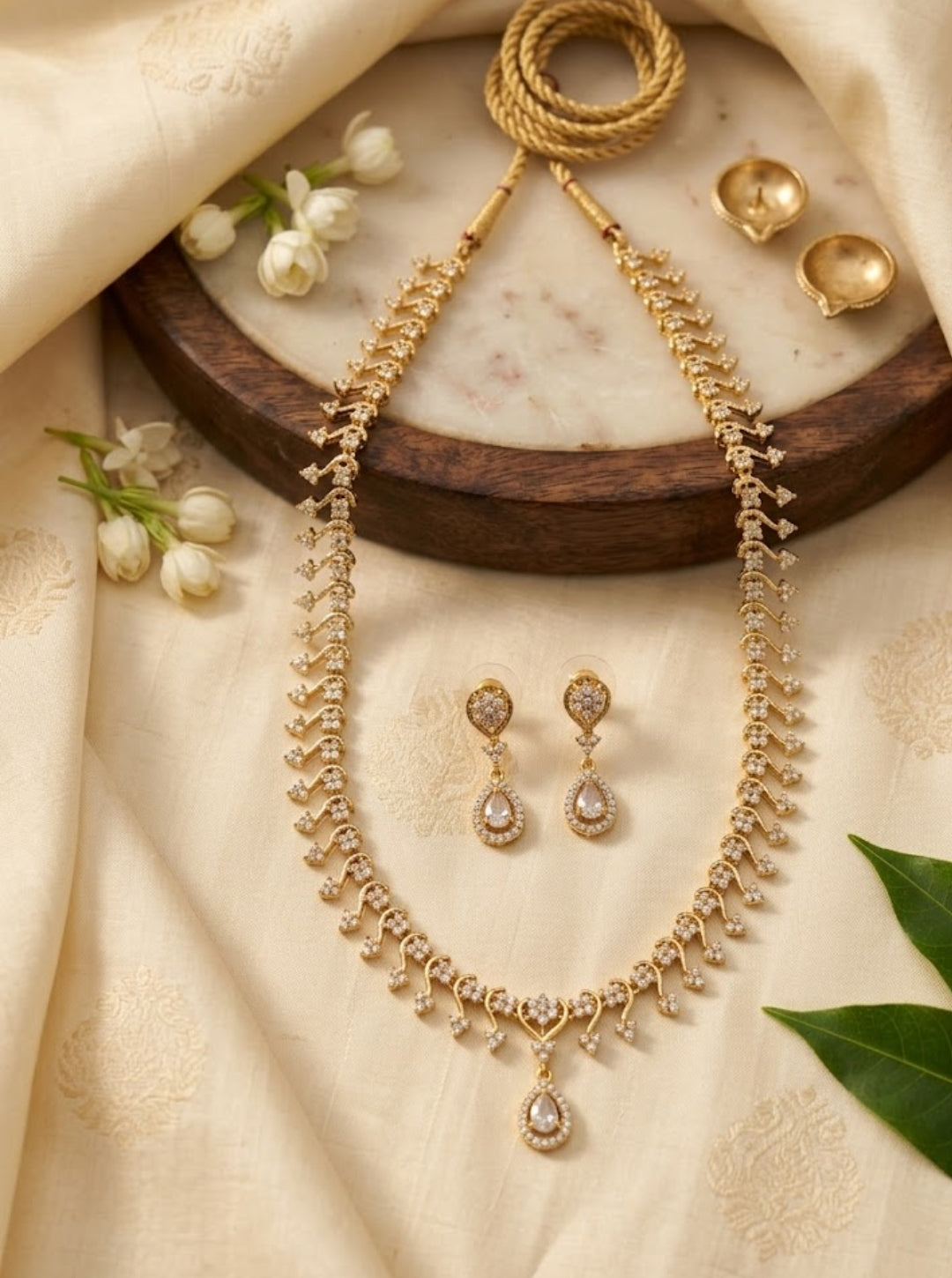 Delicate gold-toned necklace set featuring sparkling floral links, teardrop pendant and matching earrings.