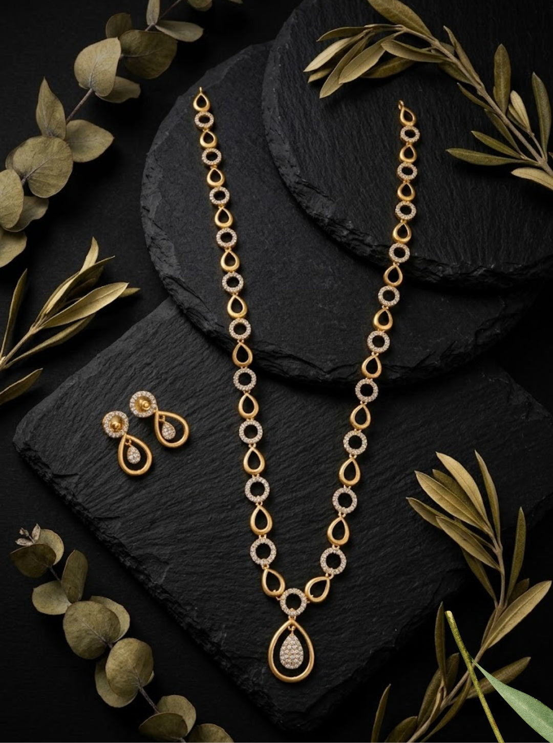 Minimal designer necklace with gold teardrop links, sparkling stone circles and matching drop earrings.