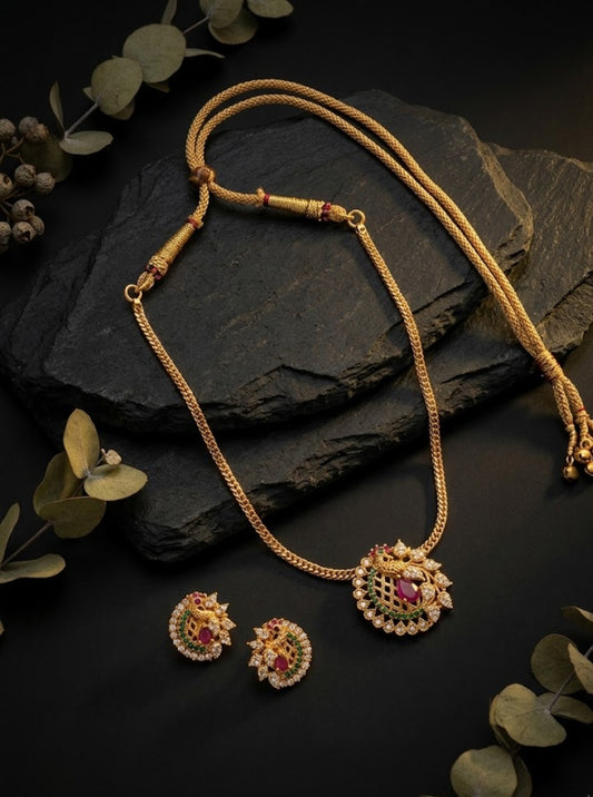 Traditional gold-toned necklace with an ornate peacock-inspired pendant and ruby green stone accents.
