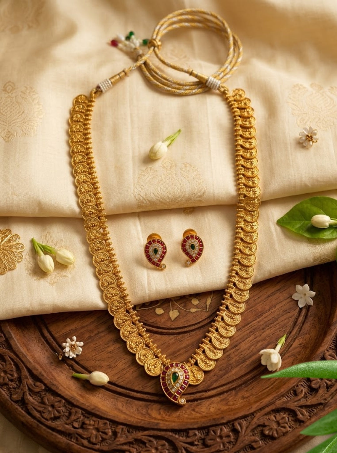 South Indian coin-style necklace featuring repeated gold motifs and an ornate ruby green pendant.