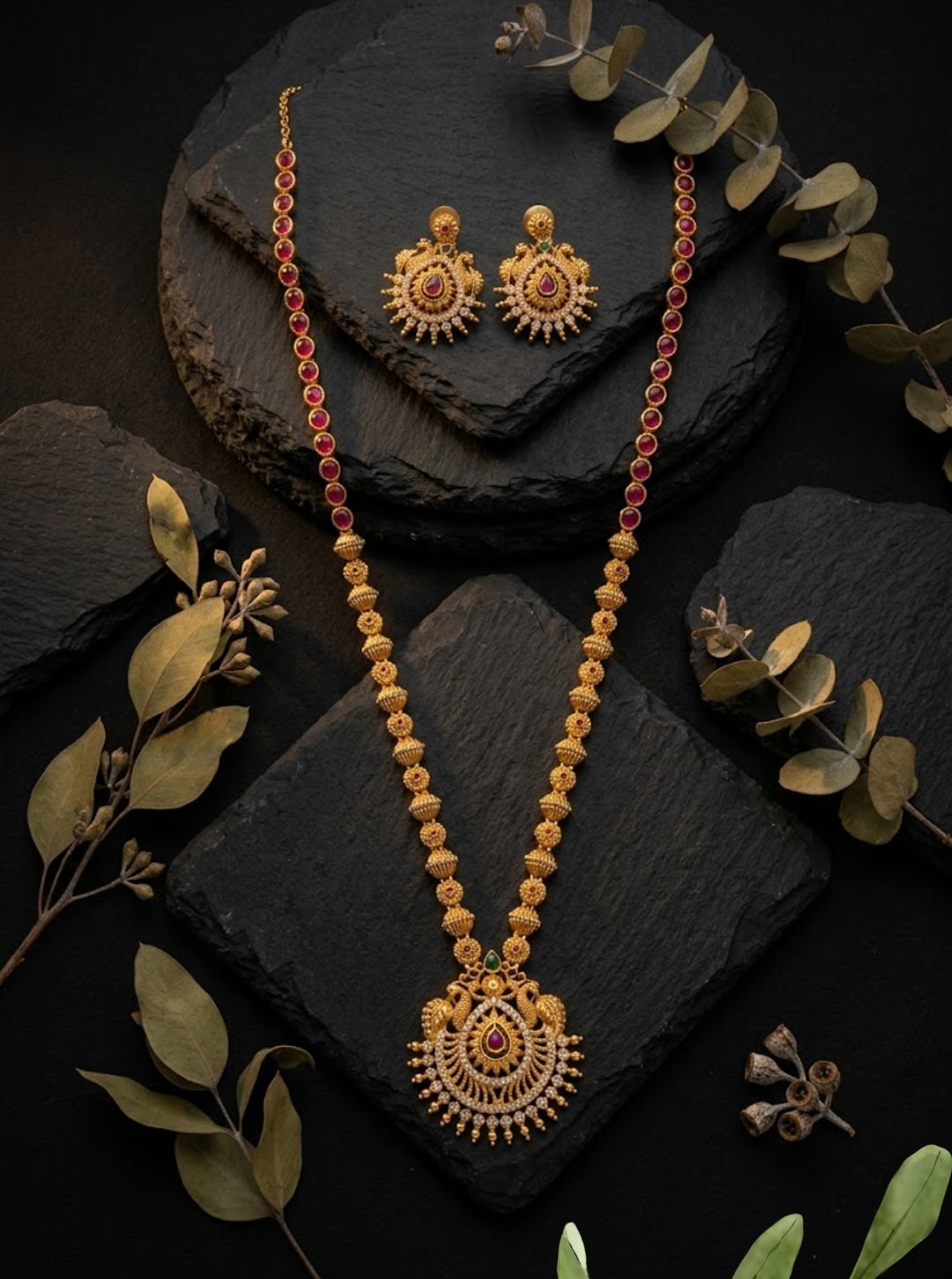 Traditional gold chain necklace with a circular gemstone pendant displayed on black slate.